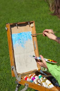 young artist working at open air, creating oil paint