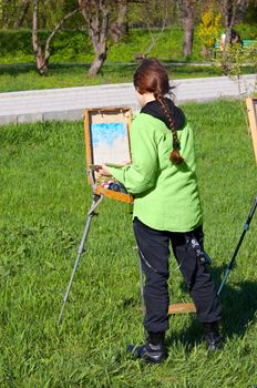 young female artist working at open air, creating oil paint