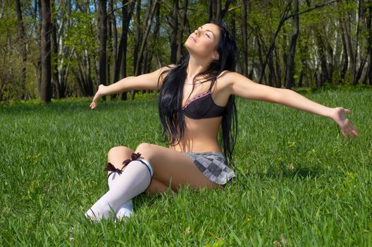 sexy brunette getting getting spring sunbath, sitting on the green grass