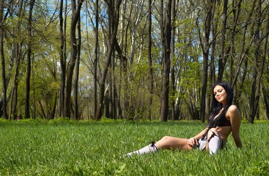sexy brunette getting spring sunbath, sitting on the green grass