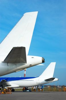 airplane tails and luggage cart on the airfield, preparing to depart