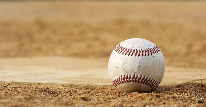 one baseball on home plate at a sports field