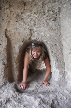 cheerful cute blond crawling in rock tunnel