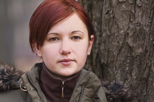 Portrait of a redheaded girl near a tree (autumn colors).