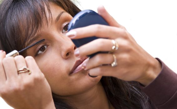 Closeup image of a young woman applying mascara.