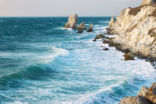 blue sea and rocks storming in light of sunset