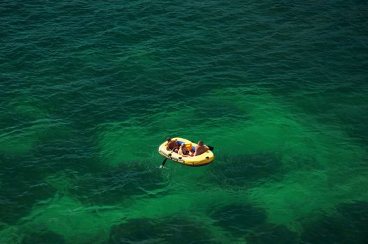 yellow inflatable boat with people floating on sea surface