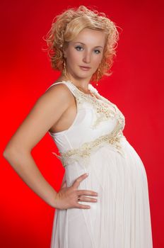 youg pregnant woman staying on red background.