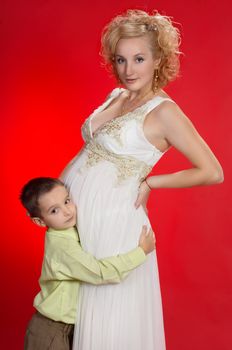 gorgeous pregnant blond woman with her first child together. on red background.