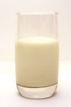 Glass filled with milk on smooth white table