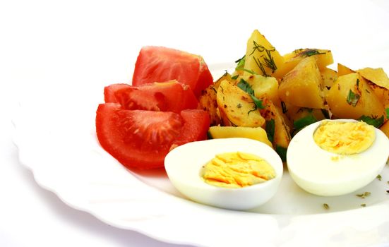 Tomatoes laying next to fried potatoes and eggs