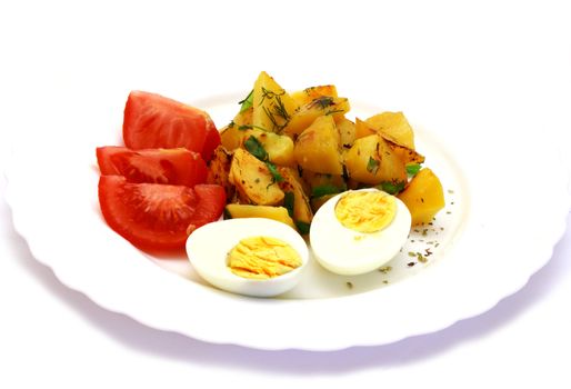 Eggs laying next to fried potatoes and tomatoes