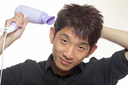 Concept image of metrosexual male featuring a young male using a hair dryer to fix his hair nicely
