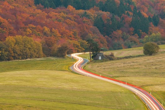 Light trails of moving vehicles on rural country road at night fall.