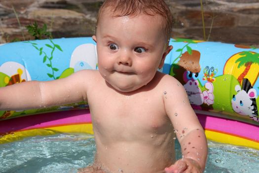 funny little kid happily splashing in the pool