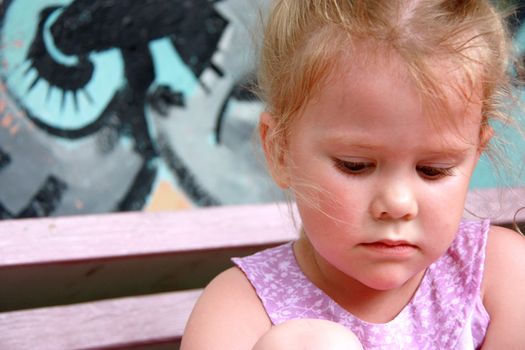 little girl sitting on a bench and cried, holding his knee