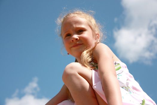 little girl sitting on blue sky background