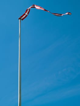 Flag of Denmark up high with clear blue sky background vertical image