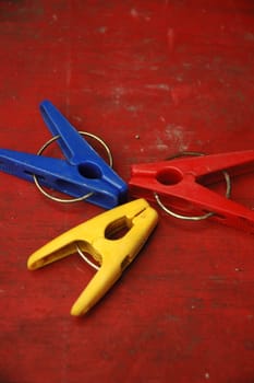 different coloured clothes pegs isolated with red background