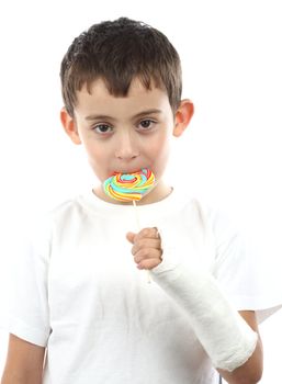 Boy with broken hand in cast, holding a lollipop over white