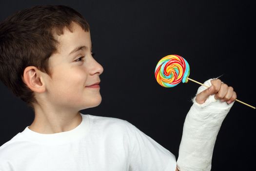 Boy with broken hand in cast, holding a lollipop