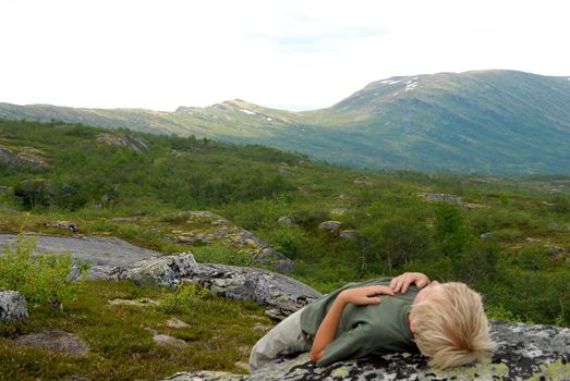 a boy lying on a stone in wild. Please note: No negative use allowed.