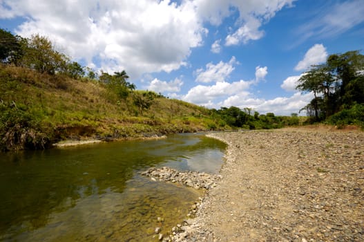 River and green nature with white clouds. Dominican Republic.