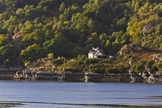 single house in rural scottish landscape with sea in front