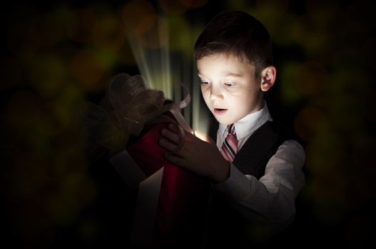 boy opens a box with a gift, beams therefrom shine and magic opens