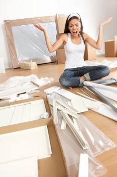 Furniture assembly frustration - woman moving in new home trying to assemble table. Funny photo of multiracial Asian Caucasian young woman.