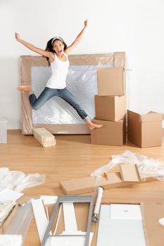 New home - moving woman excited and happy jumping of joy with moving boxes. Young Asian Caucasian woman.
