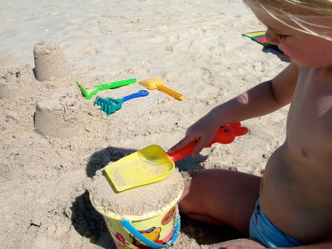 little girl playing sand on the beach. Please note: No negative use allowed.