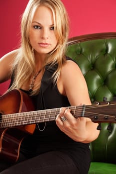 Portrait of a beautiful young woman playing guitar over red background.