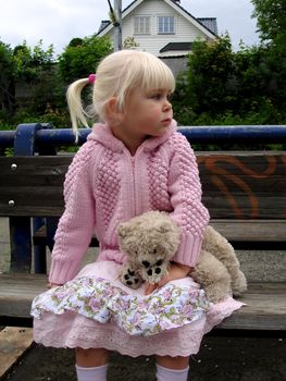 girl sitting with toy bear. Please note: No negative use allowed.