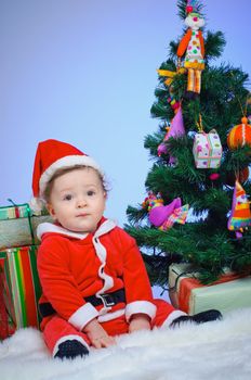 Christmas theme: little Santa - Surprised baby boy with gifts. Vertical view