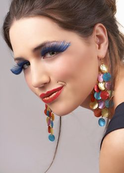 Portrait of a beautiful young brunette woman with dramatic glamour make-up and fashionable earrings