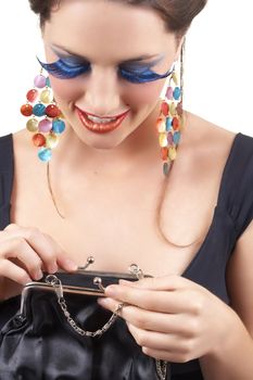 Portrait of a beautiful young brunette woman with dramatic glamour make-up and fashionable earrings looking inside her purse and smiling