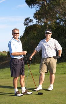 Young male golfer with his senior father ready to tee off on a beautiful summer day 