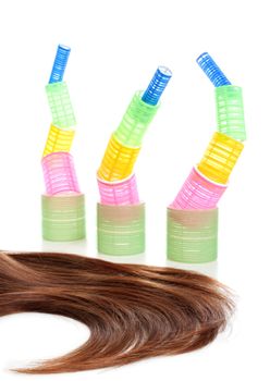 Long female brown hair and multicolored hair curlers at the background. Isolated over white background