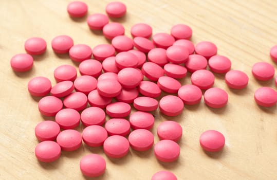 Pink pills on brown background. Shallow depth of field