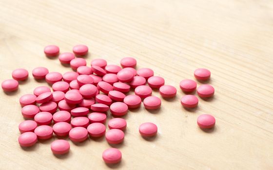 Pink pills on brown background. Shallow depth of field