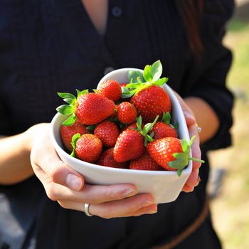 strawberry in heart shape bowl with hand