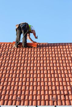 Roofer finishing laying the tiles on the roof of a building