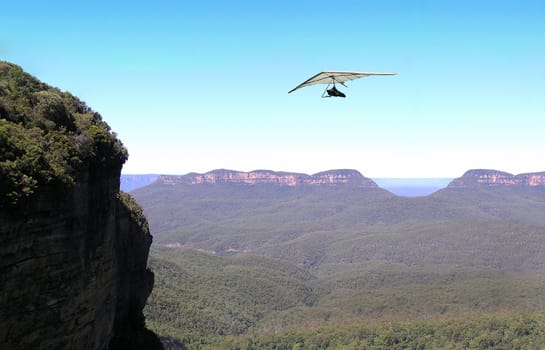 Para glider gliding over blue mountains in Australia.