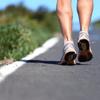 Running shoes on road - close up of runner legs, feet and running shoes with a lot of copy space