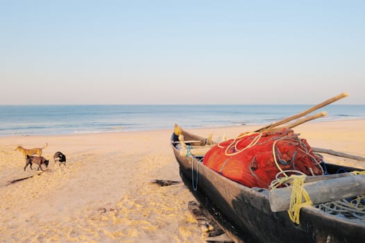 Old boat with red fishing net on sandy shore