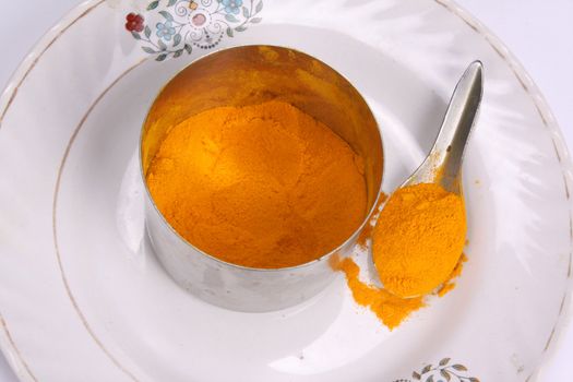 A turmeric powder bowl with a spoon, an essential spice in Indian food as well as a herbal remedy for blood purification.