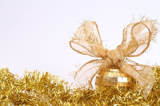 One gold Christmas bauble on yellow tinsel isolated on white background with copy space. 