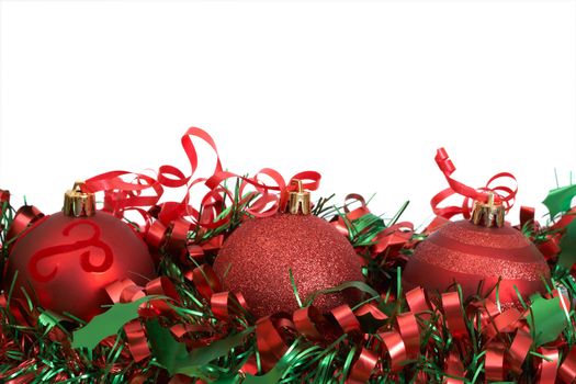 Three red Christmas baubles on green tinsel isolated on white background with copy space. 