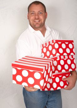 Handsome adult Caucasian man holding large Christmas gift boxes 